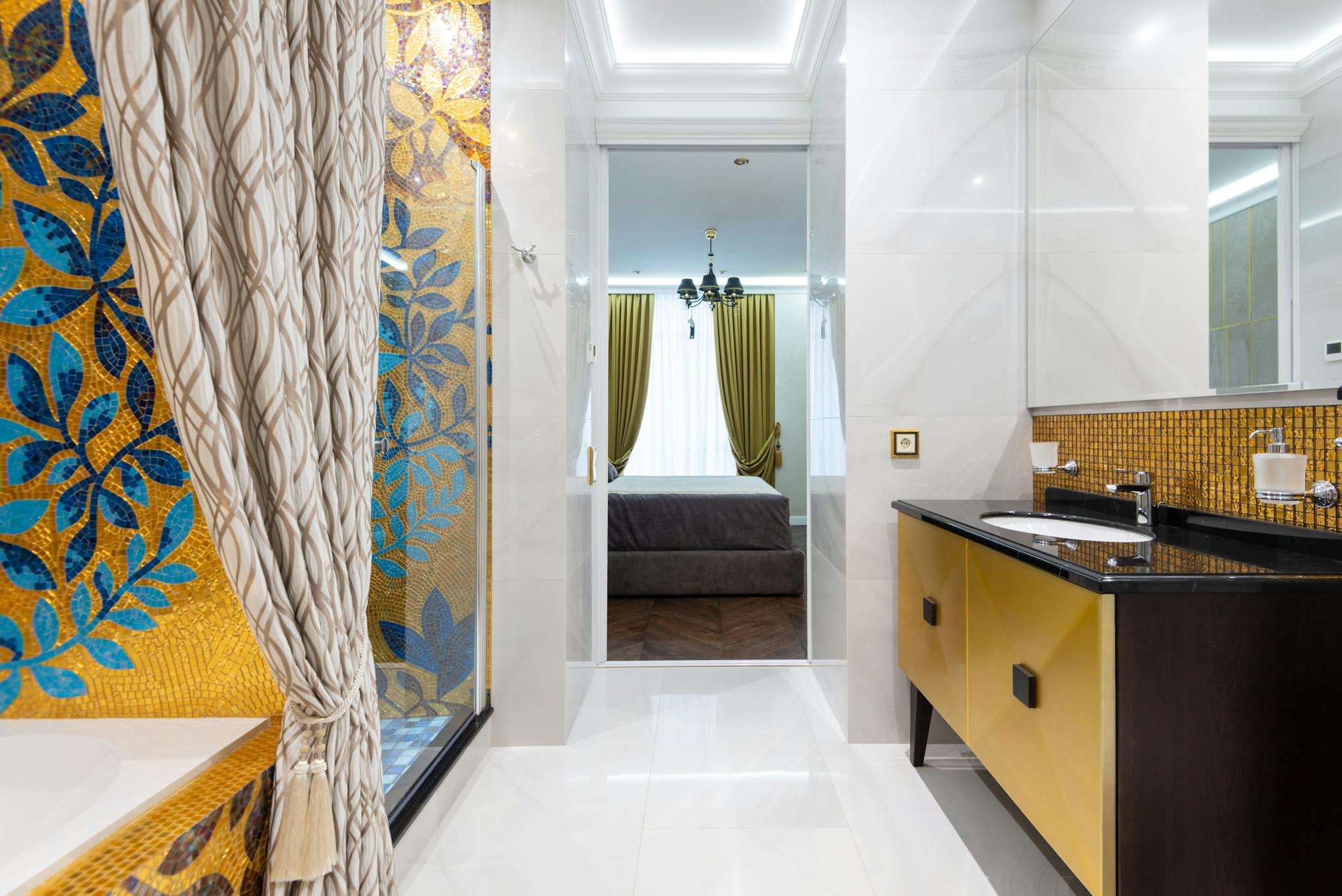 Luxury bathroom with mosaic art leading to a cozy bedroom, showcasing modern interior design.